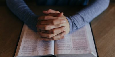 man holding his hands on open book