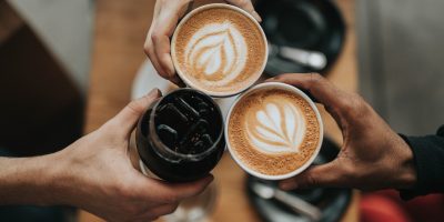 person holding cappuccino in black ceramic mug