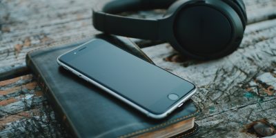 space gray iPhone 6 on book near black wireless headphones