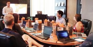 man standing in front of people sitting beside table with laptop computers